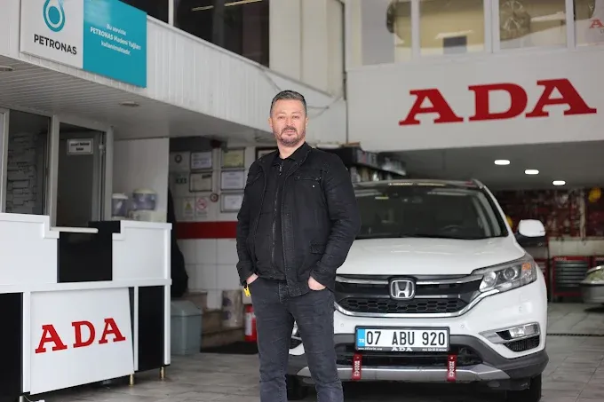 ADA Honda teknisyeni, arkasında beyaz Honda CR-V ile atölye önünde